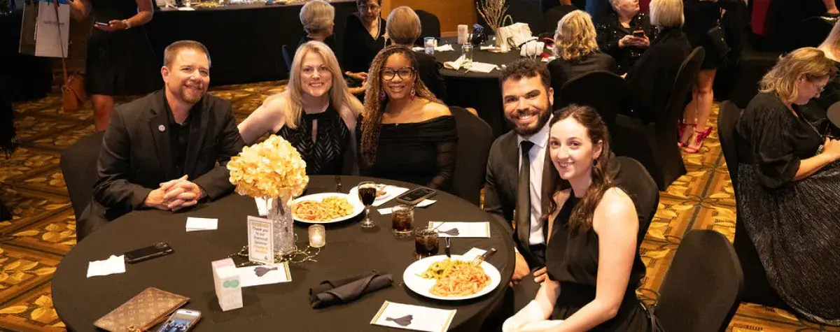 A group of individuals dine at a table during the Little Black Dress Event